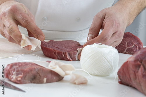 Tableau sur toile Closeup of the hands of a butcher cutting slices of raw meat off a large loin