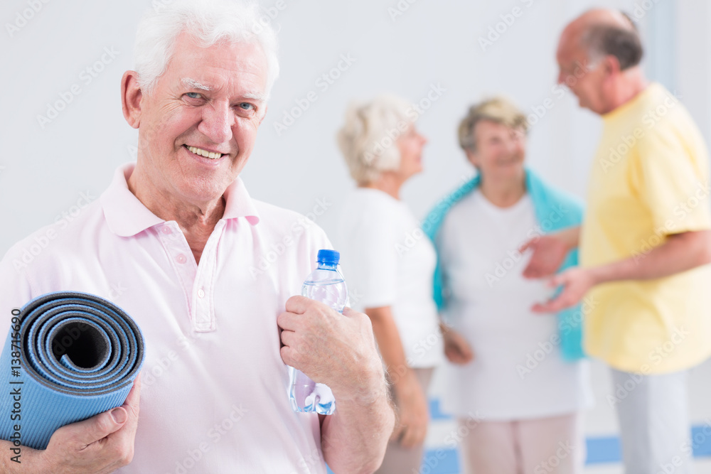 Man holding exercise mat and bottle of water