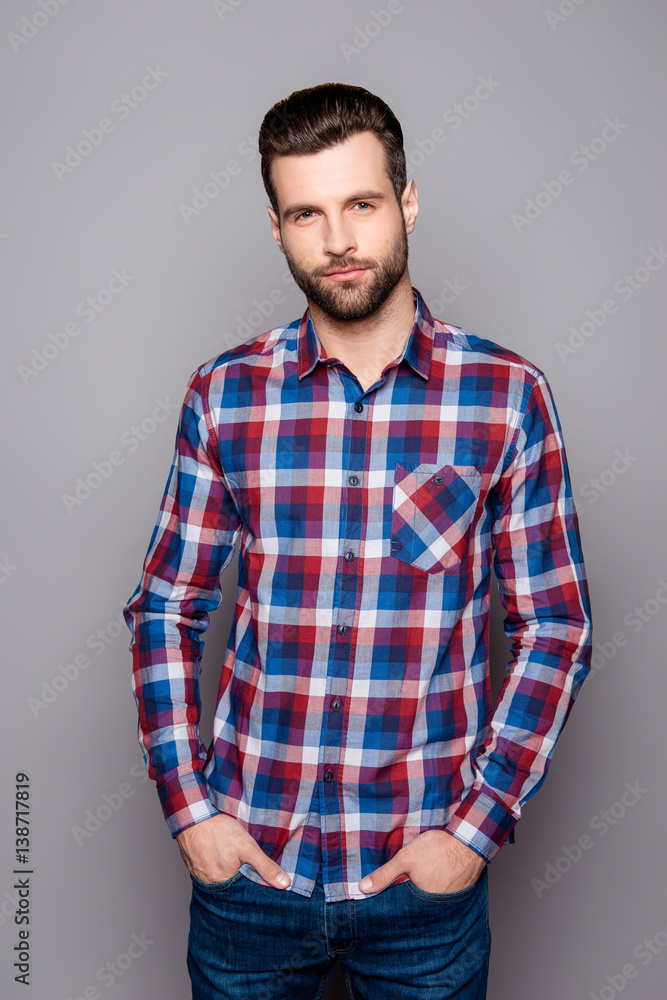 Vertical portrait of young stylisg guy in checkered shirt holding hands in his pockets Vertical portrait of young stylisg guy in checkered shirt holding hands in his pockets