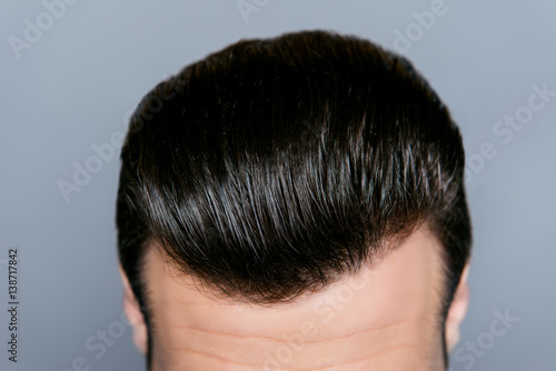 A close up of a man's stylish hairdo without dander isolated on gray background