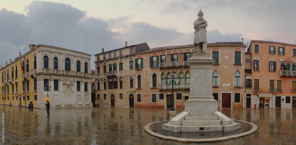 A statue is the focal point of a piazza or square on a rainy day in an often unseen part of Venice, Italy