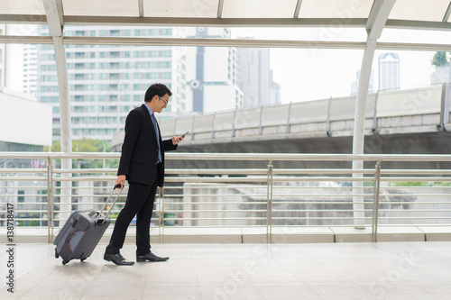 Young asian businessman using smartphone while walking outside business district © Travel man