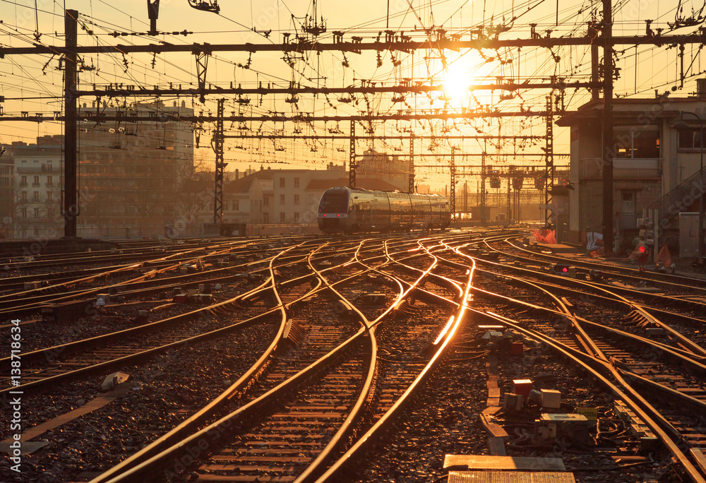 Fototapeta premium Pociąg na torach kolejowych na stacji Perrache w Lyonie (Gare de Lyon-Perrache), Francja, podczas wschodu słońca.