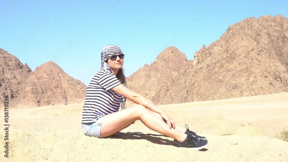Girl Waving Hand While Sitting Amid of the Desert Girl Waving Hand While Sitting Amid of the Desert