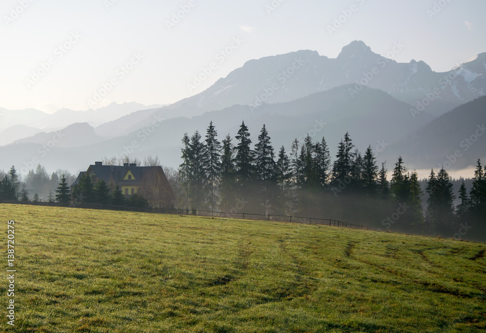 Scenic view of a wonderful valley with rural farm house building with mountains on background at sunny spring morning