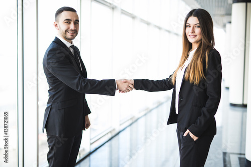 Businessman and Businesswoman shaking hands in office with big panoramic windows