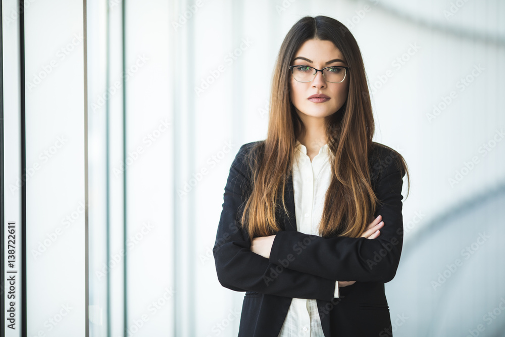 Smiling young Business woman crossed arms, standing against office Smiling young Business woman crossed arms, standing against office