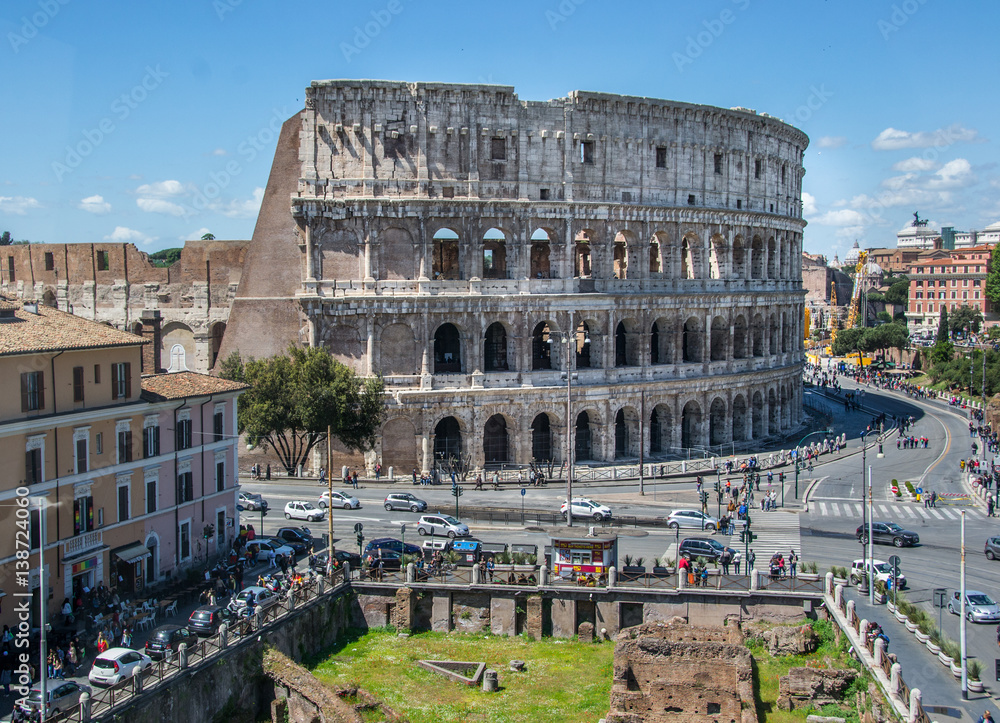 Aerial view of the Colosseum Amphitheater in Rome against blue sky background.