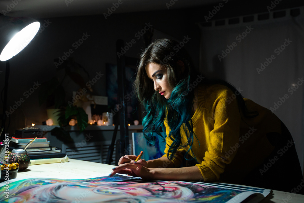Fototapeta premium Girl artist signs some of his works. Painted sign of a master. Canvas on a stretcher signature black marker.