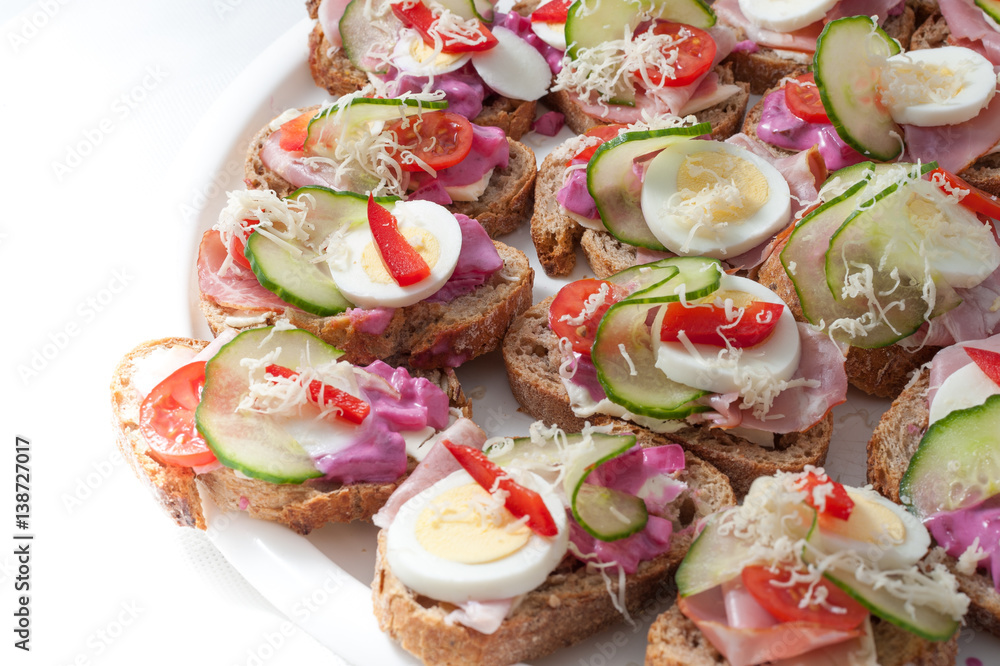 sandwiches with vegetables, ham and grated cheese on a tray sandwiches with vegetables, ham and grated cheese on a tray
