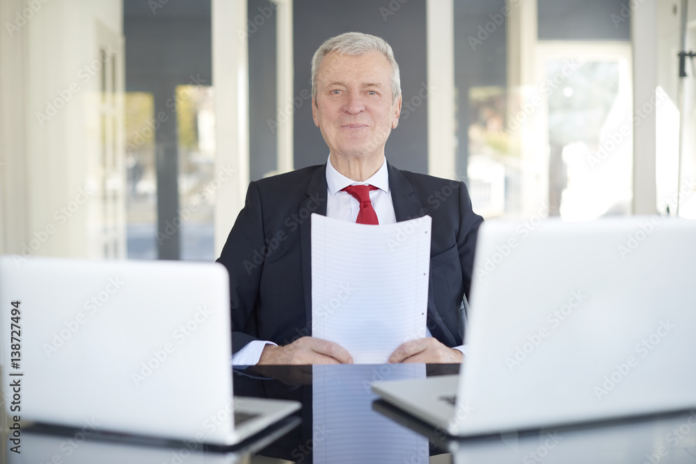 Financial businessman working online. Shot of a senior financial director sitting at desk and working on laptops in the office. Financial businessman working online. Shot of a senior financial director sitting at desk and working on laptops in the office.