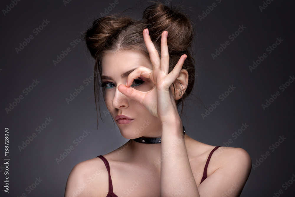 Portrait of a beautiful girl with a beautiful make-up on a gray background. The youth style. Portrait of a beautiful girl with a beautiful make-up on a gray background. The youth style.
