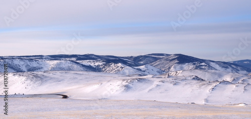 Early morning sunrise in Tazheran steppes. Snow-covered hills are colored in shades of ultra-violet. Photo toned.