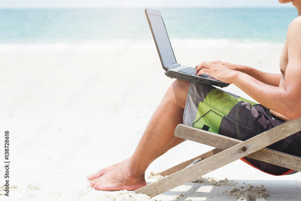Businessman working with computer on the beach. Businessman working with laptop computer on the beach. Computer work in freedom out of the office.