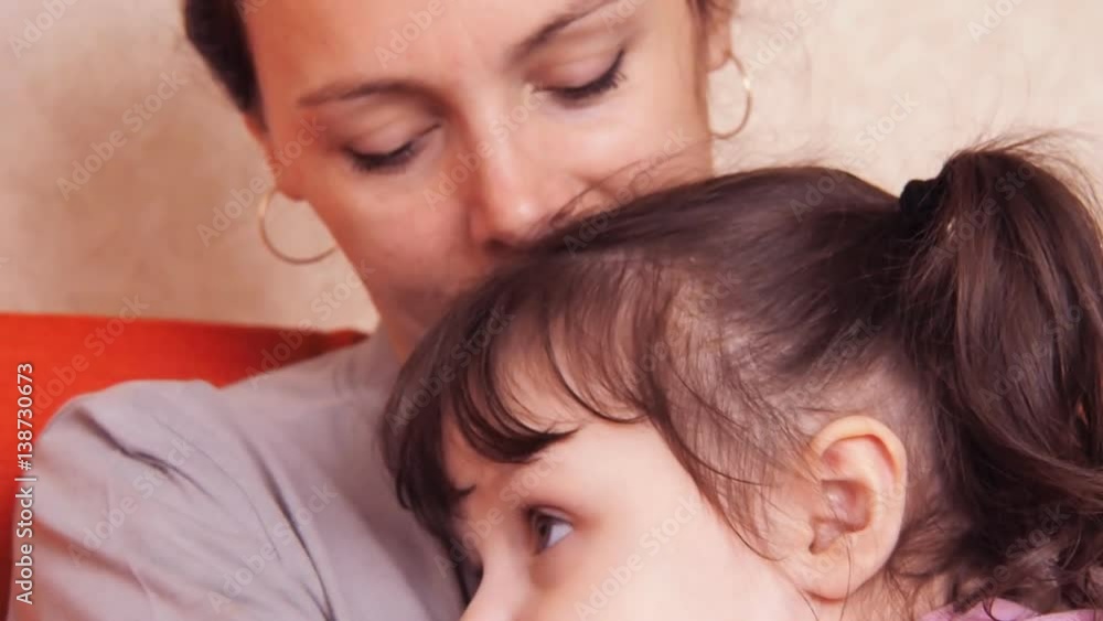 Mother hugs daughter. The daughter of a mother hugging sitting on an orange couch. Close-up. Mother hugs daughter. The daughter of a mother hugging sitting on an orange couch. Close-up.