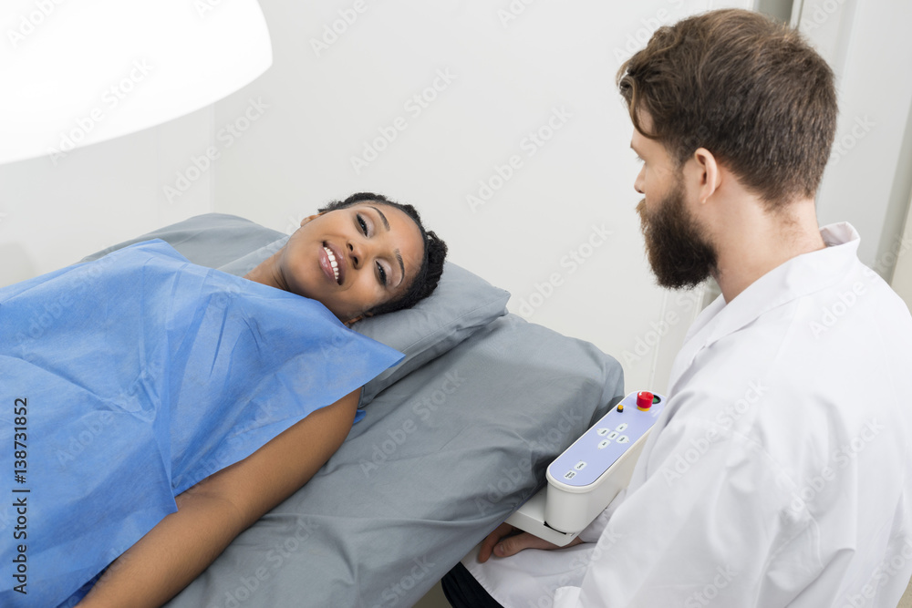 Fototapeta premium Patient Lying On Bed While Doctor Sitting In Clinic