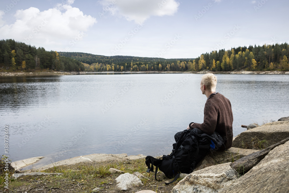 Man Sitting On Rock While Enjoying Lake View Man Sitting On Rock While Enjoying Lake View