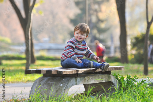 Baby sits on a bench in the park, One year old child outside
