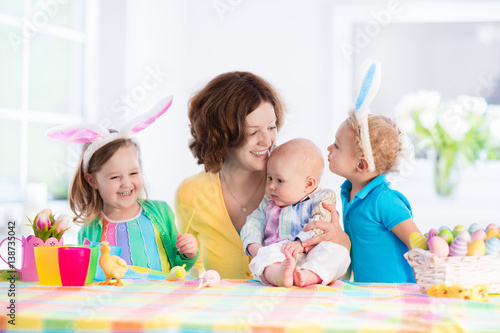 Mother with three children painting Easter eggs