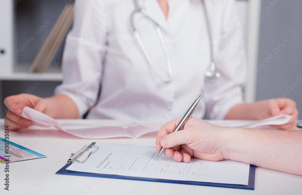 The patient completes the questionnaire in a doctor's office. Pen in hand. The image depth of field. The patient completes the questionnaire in a doctor's office. Pen in hand. The image depth of field.