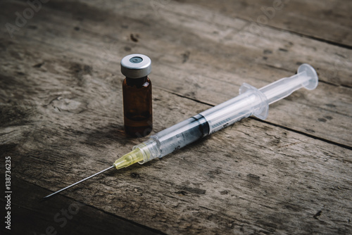 Medical injection syring with vial on wooden background. photo