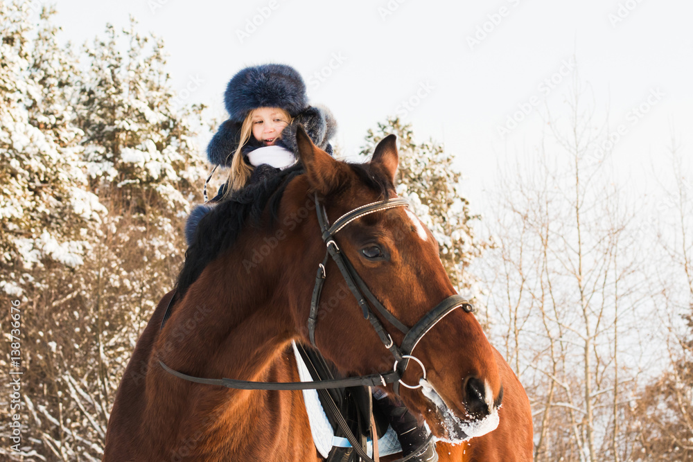 Fototapeta premium Small girl and horse in a winter