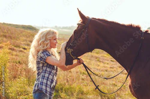 Beautiful young blonde girl is looking in her horse eyes.