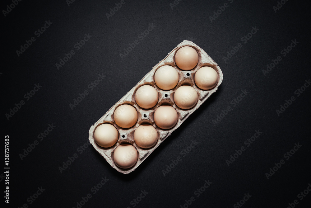 Cardboard egg box on black wooden background. Top view with copy space. Eggs container. Cardboard egg box on black wooden background. Top view with copy space. Eggs container.