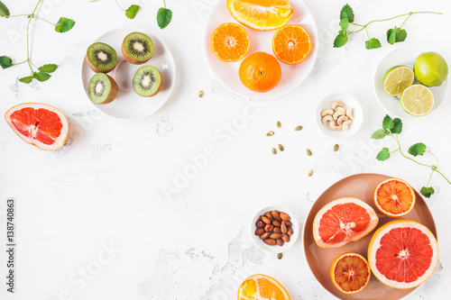 Colorful fresh fruit on white table. Orange, tangerine, lime, kiwi, grapefruit. Summer fruit. Flat lay, top view, copy space