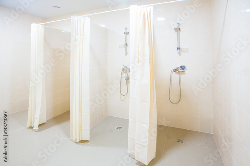 Public shower room with several showers. Big  light  empty public shower room  with bright walls and gray floor