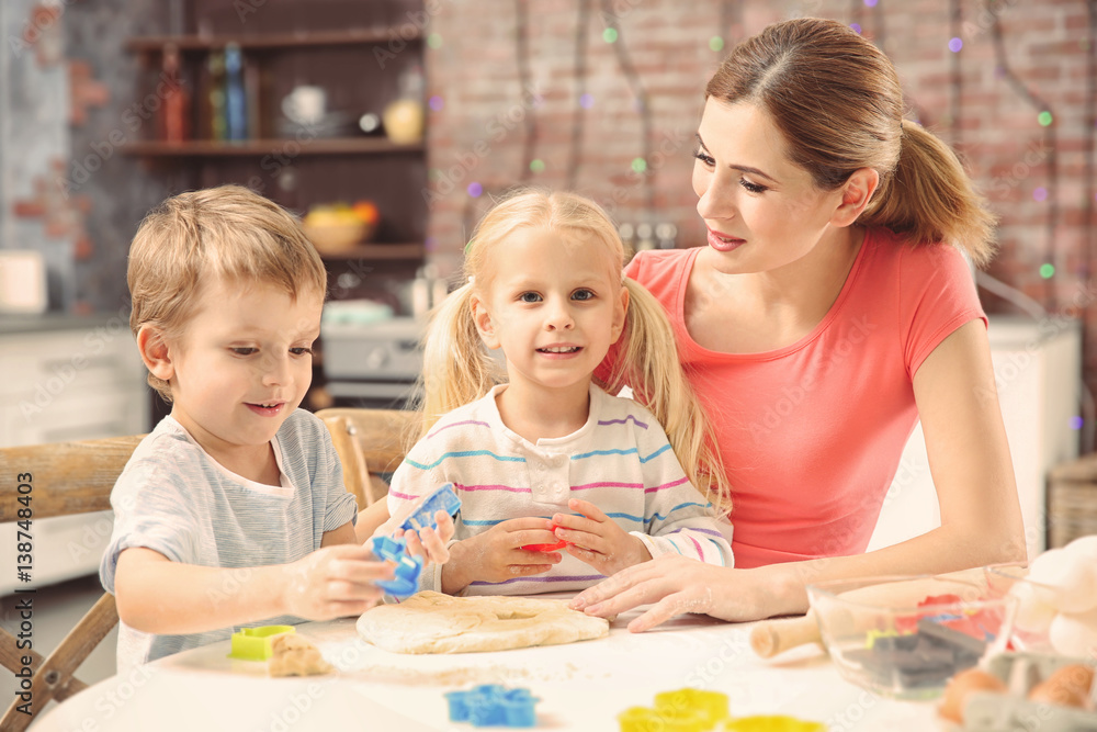Fototapeta premium Young mother with kids making biscuits on table