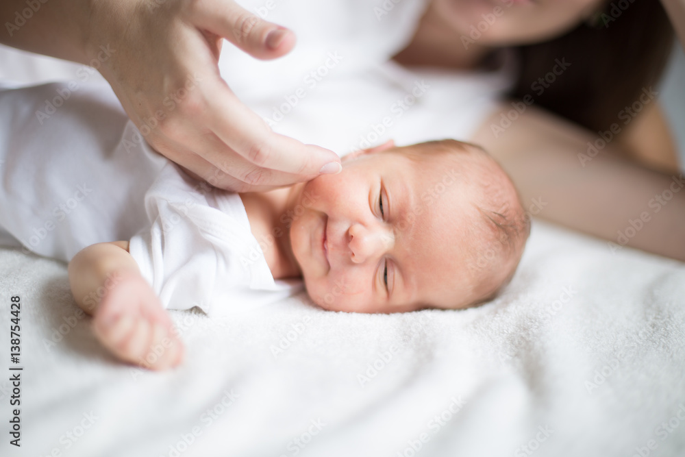 mother caressing a newborn baby lying on the bed mother caressing a newborn baby lying on the bed