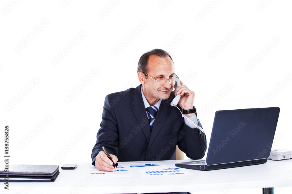 Confident businessman in the workplace in the office of a laptop talking on the phone Confident businessman in the workplace in the office of a laptop talking on the phone