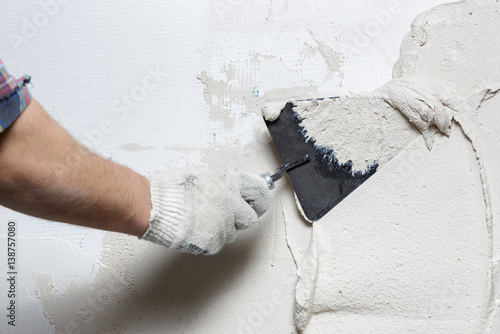 Construction worker with trowel plastering a wall photo