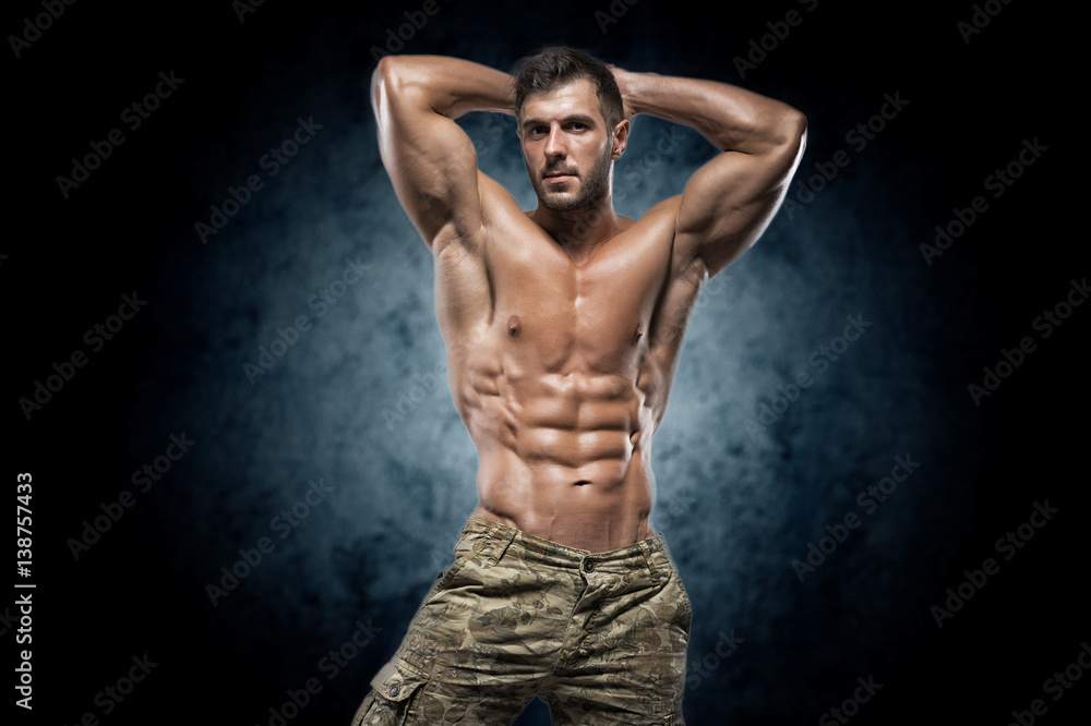 Muscular young man in studio on dark background Muscular young man in studio on dark background