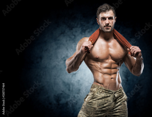 Muscular young man in studio on dark background