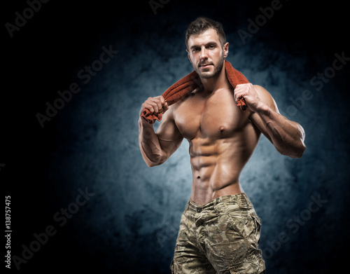 Muscular young man in studio on dark background © bondarchik