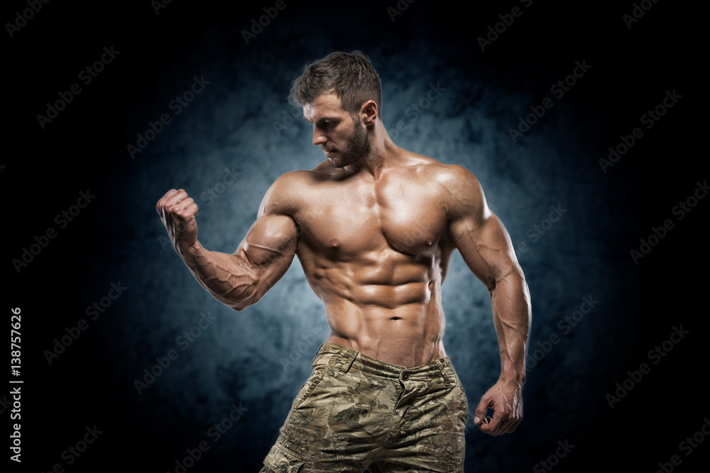 Muscular young man in studio on dark background Muscular young man in studio on dark background