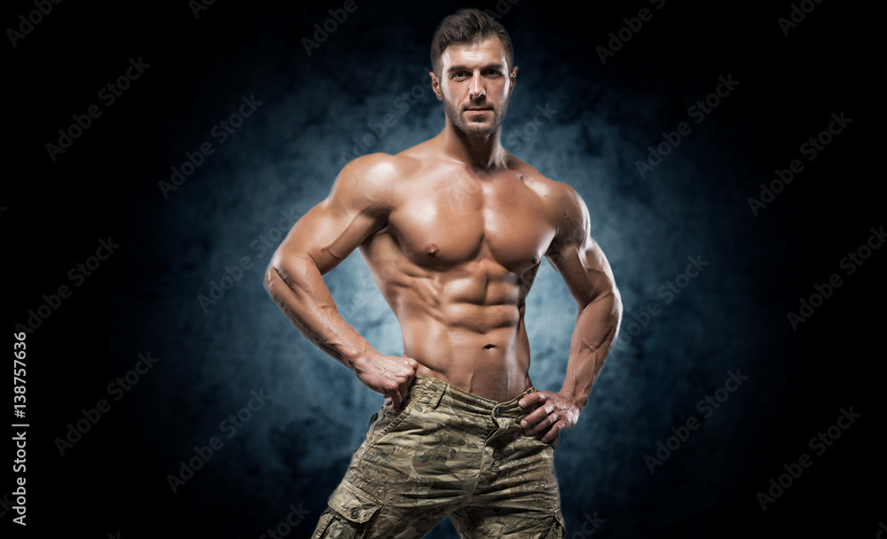 Fototapeta premium Muscular young man in studio on dark background