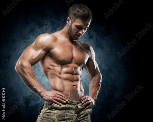 Muscular young man in studio on dark background