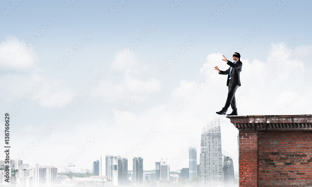 Danger and risk concept with businessman making step from edge Danger and risk concept with businessman making step from edge