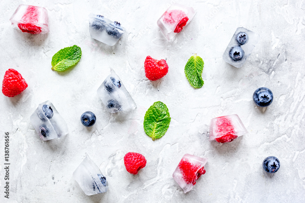 Bueberrie and raspberrie in ice cubes on stone top view Bueberrie and raspberrie in ice cubes on stone top view