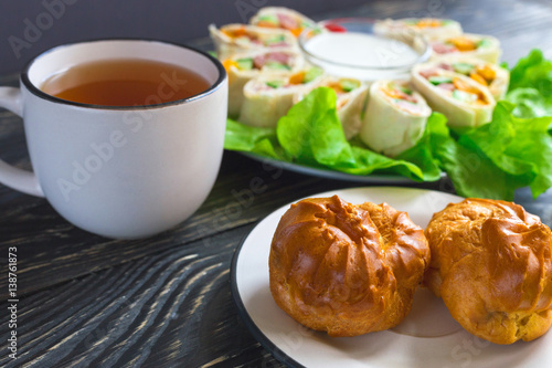 Pita rolls with lettuce, sauce, chili pepper, eclairs and tea