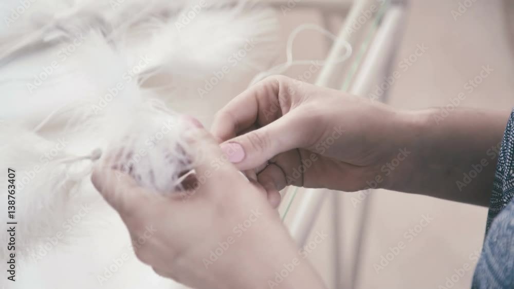 Dreamcatcher: the process of creating. Close-up of female hands glued white feathers and beads to the white thread. Macrame. Sleight of hand, and needlework. Macrame. Dreamcatcher: the process of creating. Close-up of female hands glued white feathers and beads to the white thread. Macrame. Sleight of hand, and needlework. Macrame.