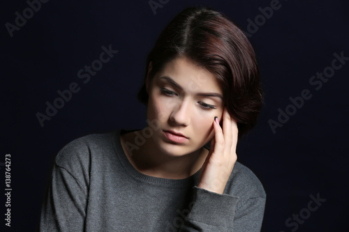 Depressed young woman on black background