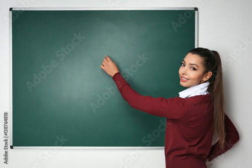 Beautiful young teacher writing on blackboard in classroom © Africa Studio