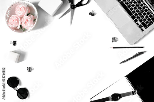 White office desk frame with laptop keyboard and supplies. Laptop, notebook, pen, roses, sunglasses, clips, pencil, scissors, watch and office supplies on white background. Flat lay, top view, mockup photo