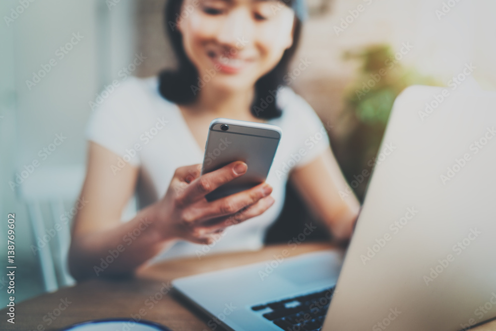 Young smiling Asian woman spending rest time at home and using smartphone for texting message.Selective focus on mobile phone. Blurred background. Young smiling Asian woman spending rest time at home and using smartphone for texting message.Selective focus on mobile phone. Blurred background.