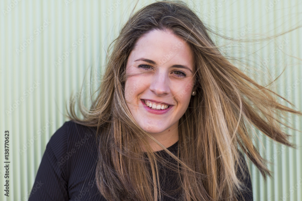 Fototapeta premium outdoors portrait of a young woman smiling. Green background