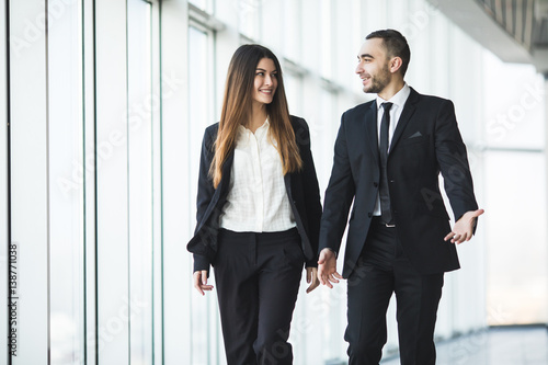 Confident business partners walking down in office and talking